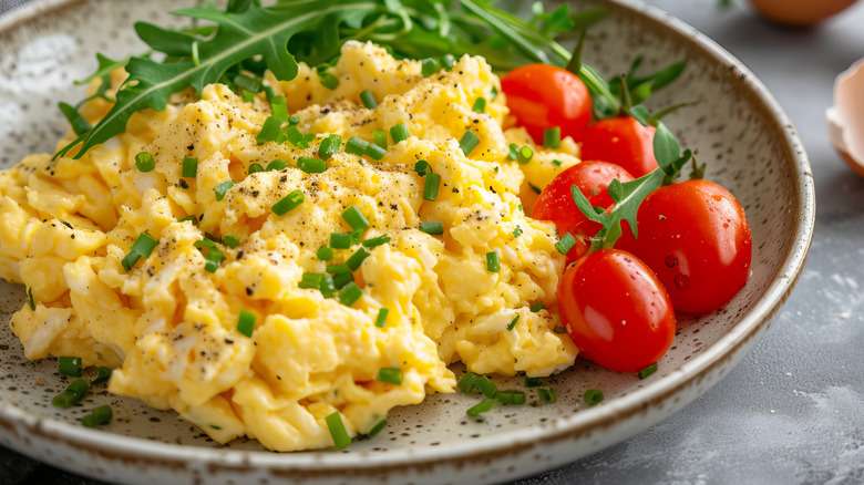 Scrambled eggs with tomatoes, chives, arugula served in a bowl