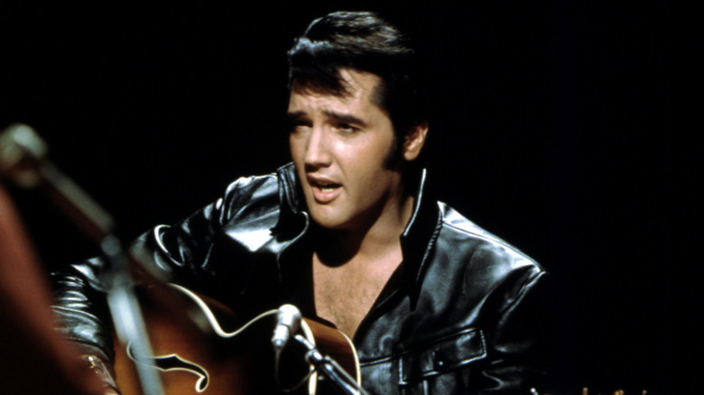 Elvis Presley plays a guitar in his leather outfit for his famed comeback special in 1968