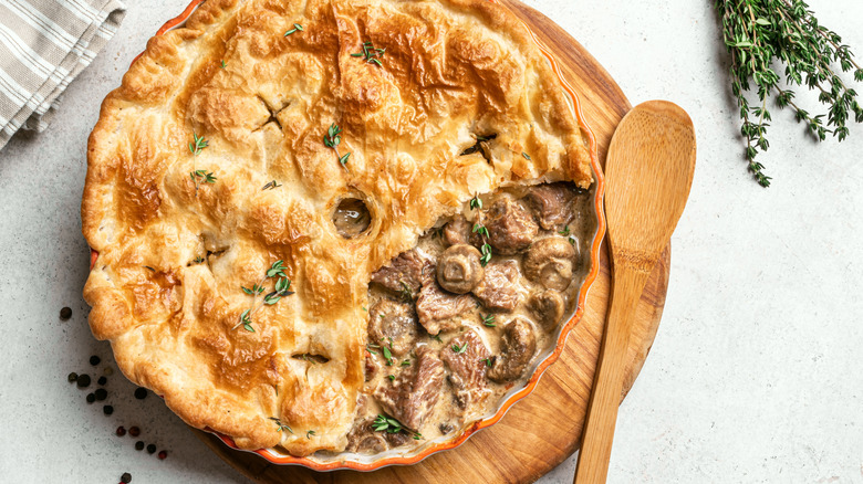 A baked mushroom and beef pie on a cutting board.