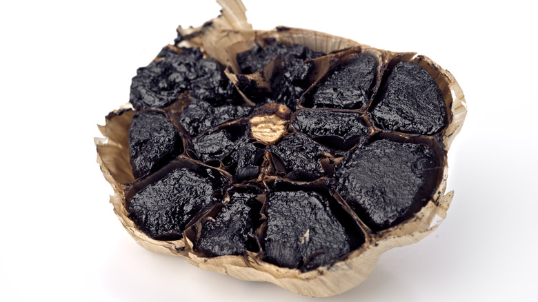 A clove of black garlic in front of a white background