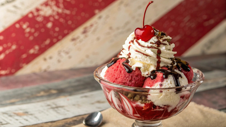 Ice cream sundae with chocolate syrup and a cherry in a glass bowl