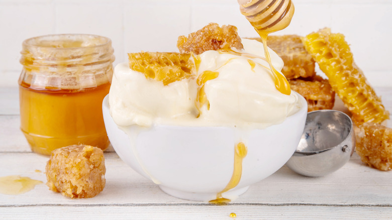 Drizzling honey over vanilla ice cream in a bowl