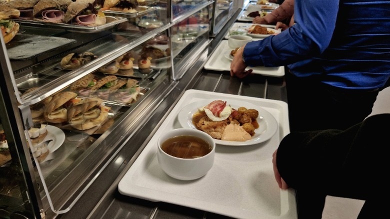 A person assembling their tray in a cafeteria.