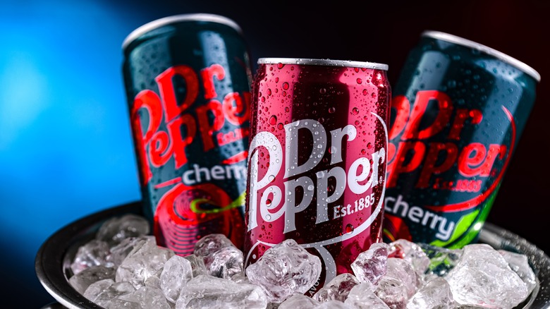 A can of Dr Pepper flanked by two cans of cherry Dr Pepper in a bucket of ice