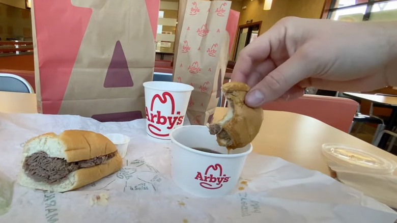 Hand dipping French Dip & Swiss sandwich into sauce