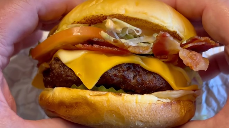 Hands holding Big Cheesy Bacon Burger