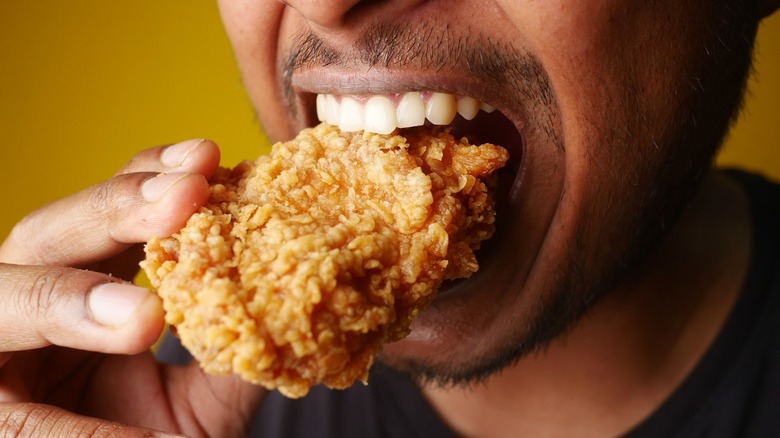 Person taking a bite of fried chicken