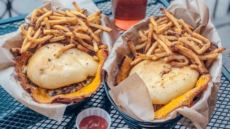 Two baskets of burgers with cheese skirts and fries from the Skirted Heifer