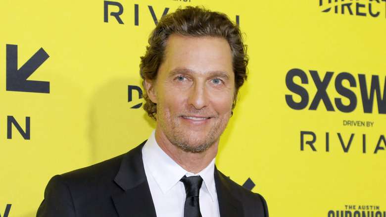 Matthew McConaughey posing in front of a yellow background at a red carpet event