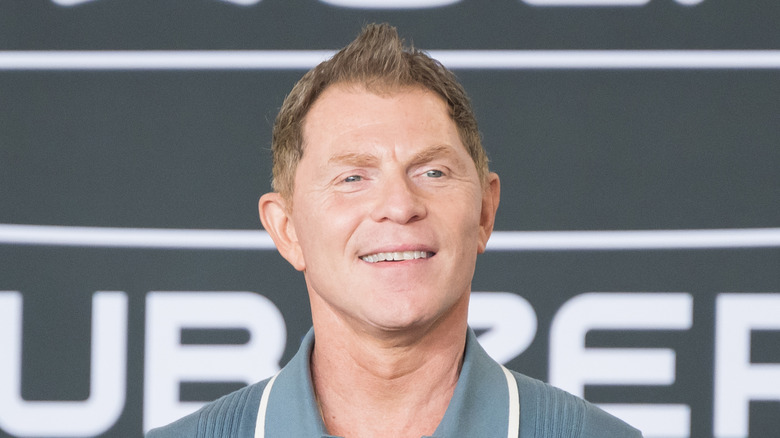 Bobby flay smiling wearing a blue shirt at an event.