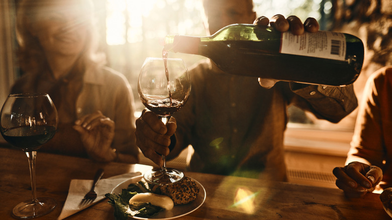 Man pouring red wine into his glass at restaurant bar