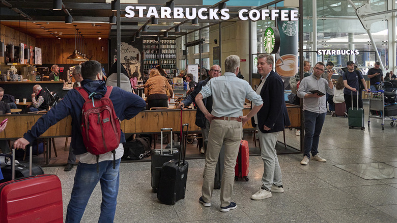 Travelers standing with luggages at a Starbucks inside an airport