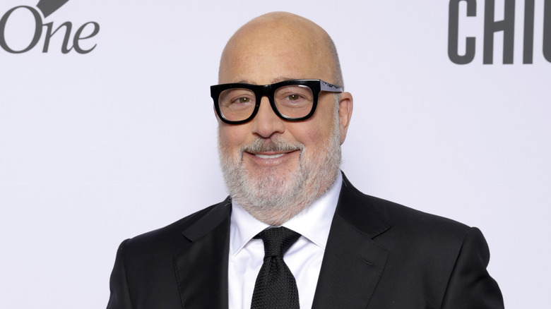 Andrew Zimmern wearing a black suit and smiling