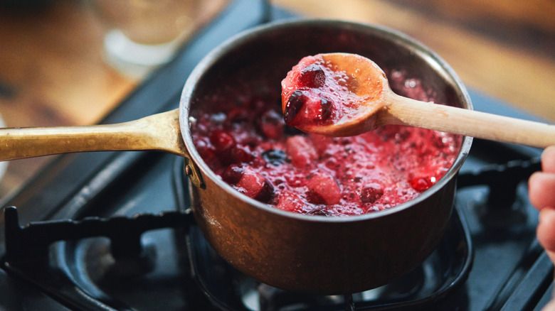 Close-up of a wooden spoon dipping into a pot of homemade cranberry sauce