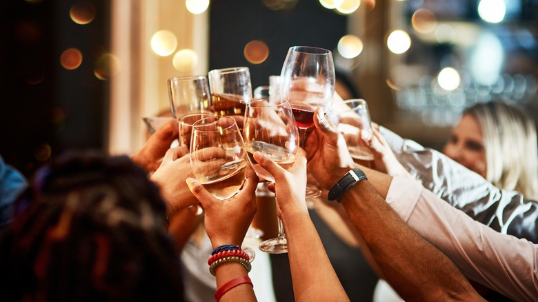A group of people clinking together various drinks