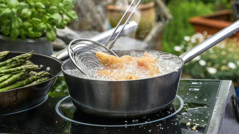 Food in pot of bubbling oil on stove