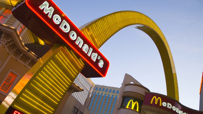 A Neon McDonald's sign apart of a larger McDonald's Golden Arch outside of a McDonald's location.