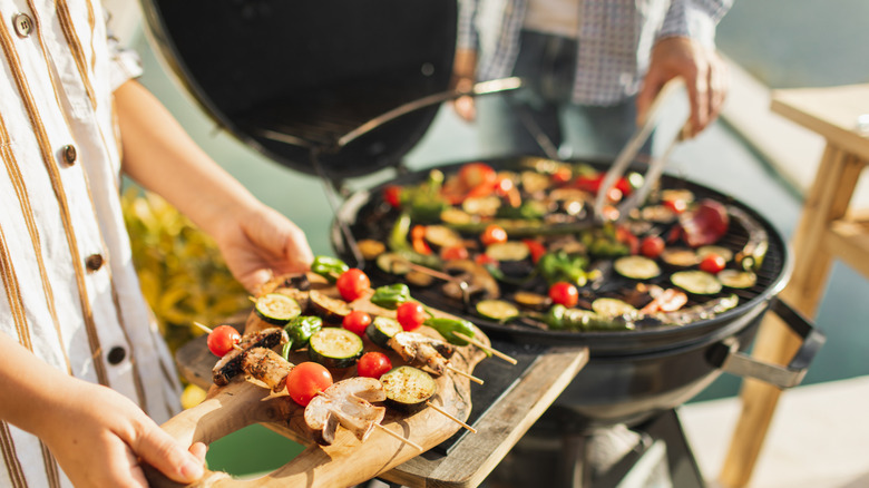 A couple grills vegetables outside on grill
