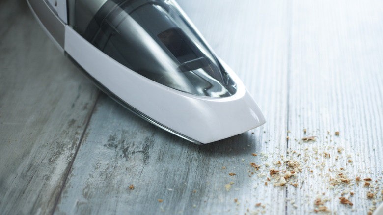 Mini vacuum vacuuming crumbs off wood floor