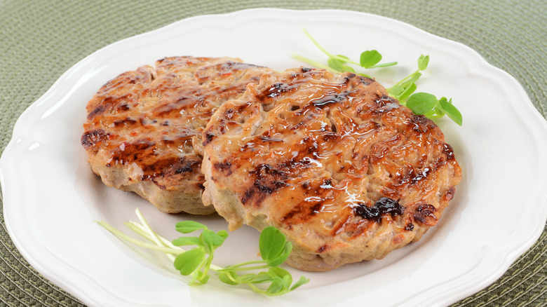 Grilled turkey burgers on a white plate garnished with greens
