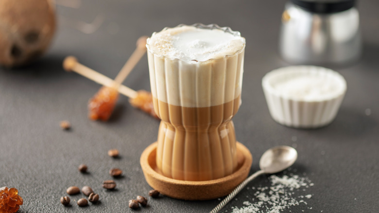 Glass of Vietnamese coffee with a spoon, garnished by coffee beans and rock sugar