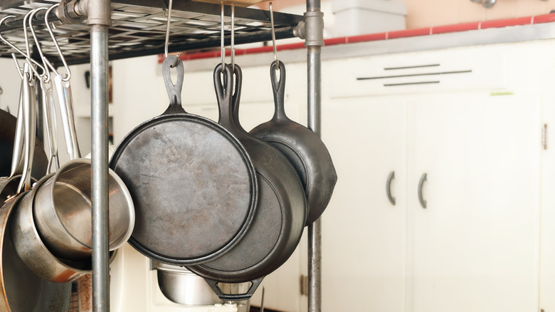 Cast iron skillets hang from a pot rack