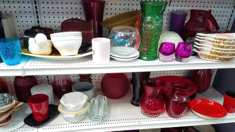 Vintage dishware of various types rest on a shelf in a thrift store