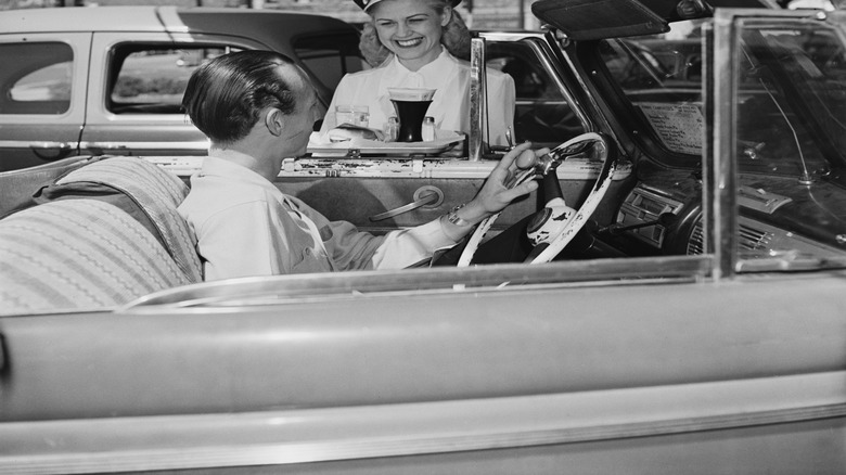 Black and white photo of fast food employee serving man in car