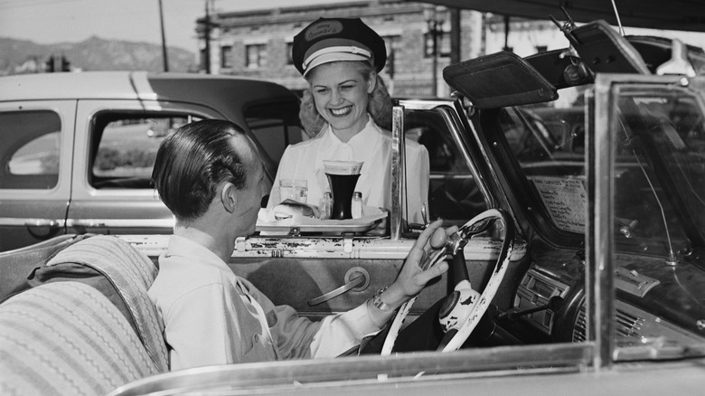 Black and white photo of fast food employee serving man in car