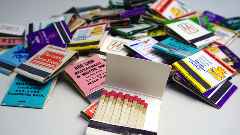A pile of matchbooks with different business names on a table