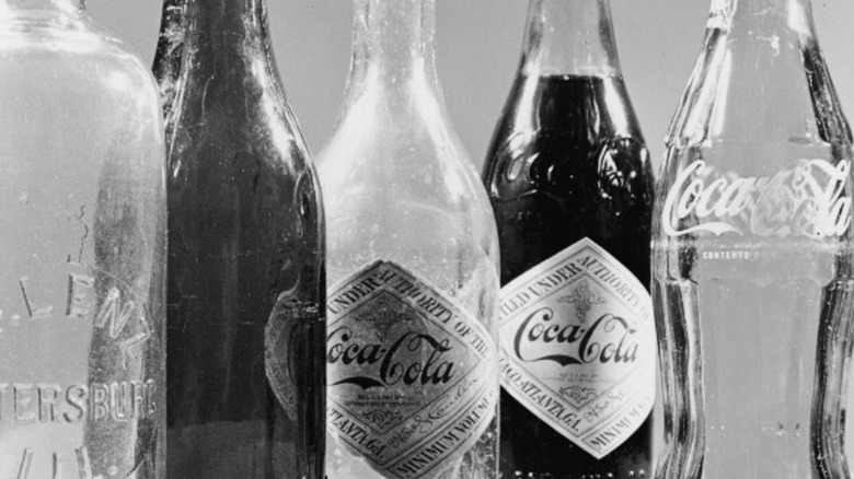 Black and white photo of five vintage glass Coca-Cola soda bottles