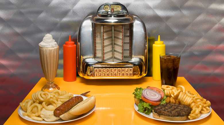 Diner table with milkshake, burger, hot dog, and curly fries