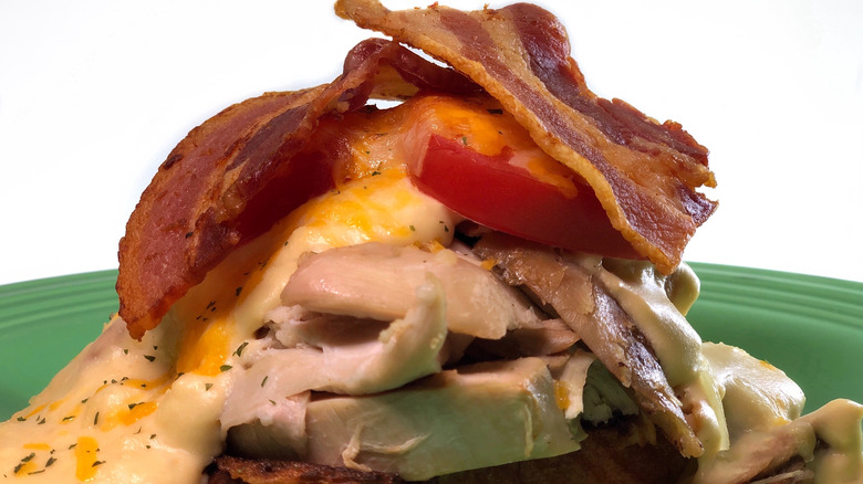 Closeup of open faced sandwich with turkey, sauce, bacon, tomato