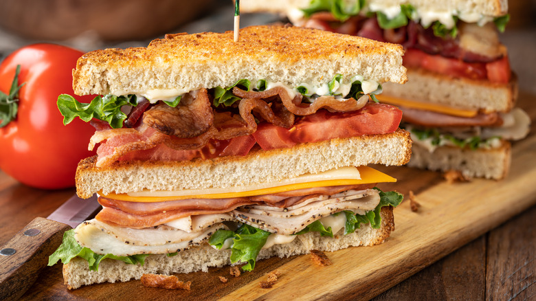 Club sandwich cut in half on wood board