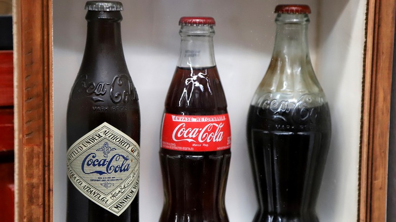 Three vintage Coke bottles in a display case