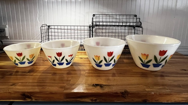 Four Fire-King tulip mixing bowls on wooden counter.