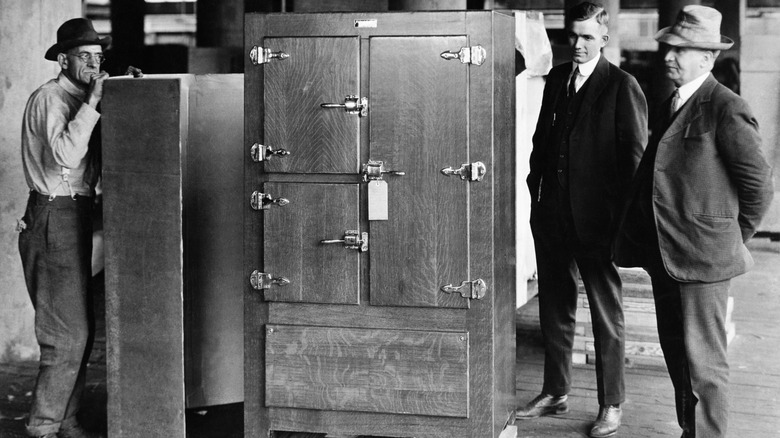 Men examine a wooden refrigerator in 1918