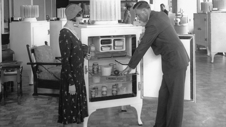A 1920s salesman shows a refrigerator to a female shopper