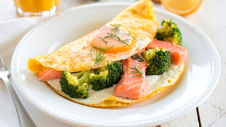 Omelet with broccoli and chunks of salmon on white plate