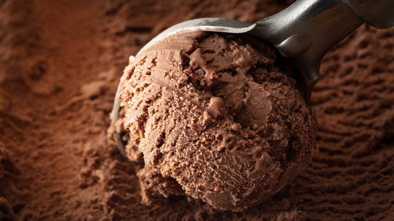 Chocolate ice cream with metal ice cream scoop making scoop through it