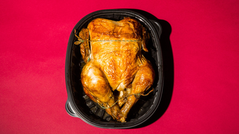 An overhead view of a rotisserie chicken in a plastic container