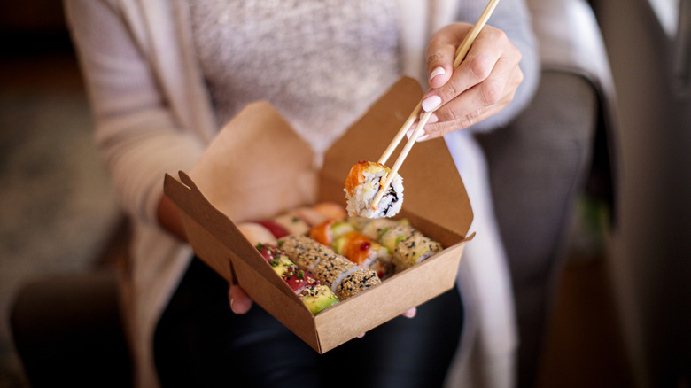 Person eating takeout sushi