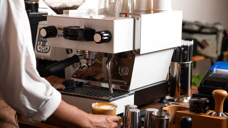 A barista finishing a drink with a professional, single grouphead espresso machine
