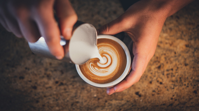 A skilled barista pouring a rosetta in a cappuccino