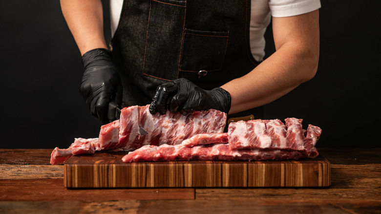 butcher cutting into rack of ribs
