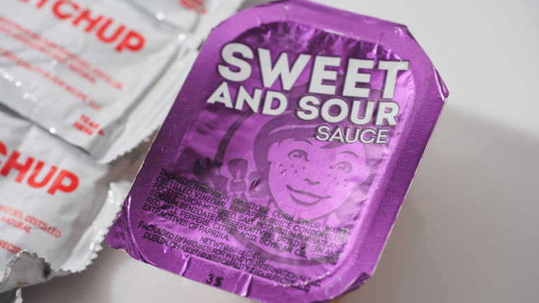 Container of Wendy's sweet and sour sauce next to ketchup