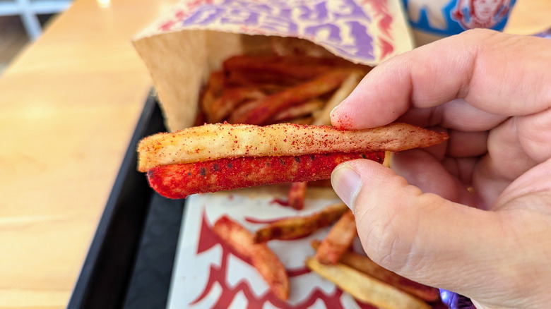 Hand holding Takis fry and Takis chip