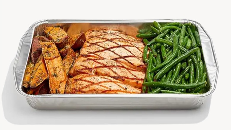 Whole Foods paleo grilled salmon with green beans and sweet potatoes Family Meal in foil tray on a white background.