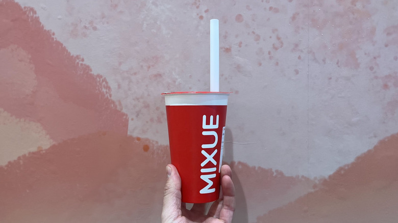 Hand holding a red cup with a straw