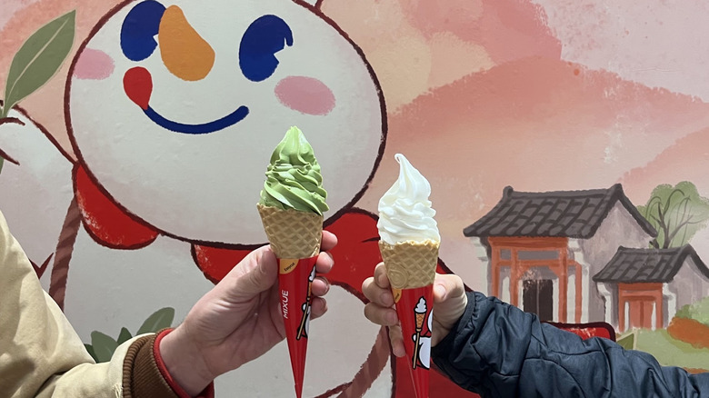 Two hands holding soft serve ice creams at Mixue